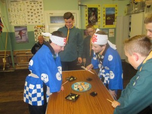 Scouts dressed in Japanese costume about to eat sushi.